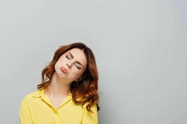 offended woman with closed eyes posing on grey