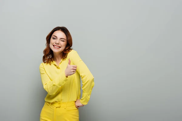 Happy Woman Winking Showing Thumb While Standing Hand Hip Grey — Stock Photo, Image