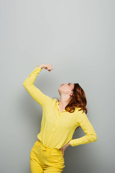 woman in yellow shirt demonstrating strength on grey