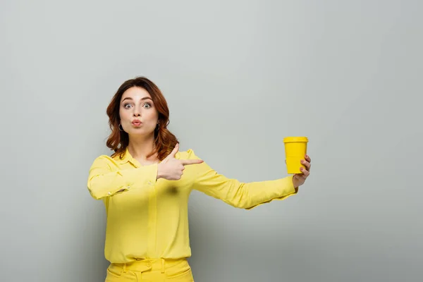 Podekscytowana Kobieta Patrząc Aparat Wskazując Żółty Papierowy Kubek Szarości — Zdjęcie stockowe