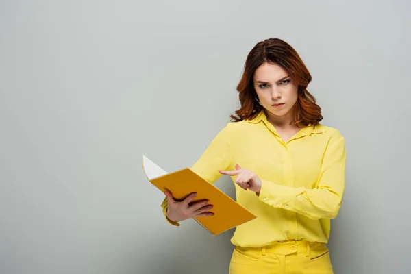 Mulher Rigorosa Olhando Para Câmera Enquanto Aponta Para Notebook Cinza — Fotografia de Stock