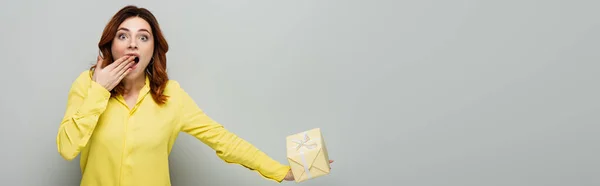 Astonished Woman Covering Mouth Hand While Holding Gift Box Grey — Stock Photo, Image