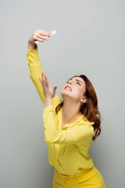 Grinin üstünde akıllı telefondan selfie çekerken yalvaran bir kadın.