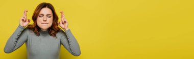 tense woman with crossed fingers standing with closed eyes on yellow, banner clipart