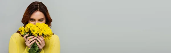 Радостная Женщина Пахнущая Желтыми Цветами Глядя Камеру Изолированную Сером Баннер — стоковое фото