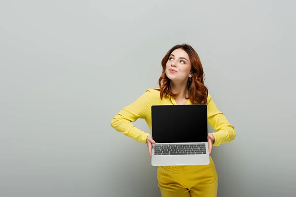 Усміхнена Жінка Дивиться Геть Тримаючи Ноутбук Порожнім Екраном Сірому — стокове фото