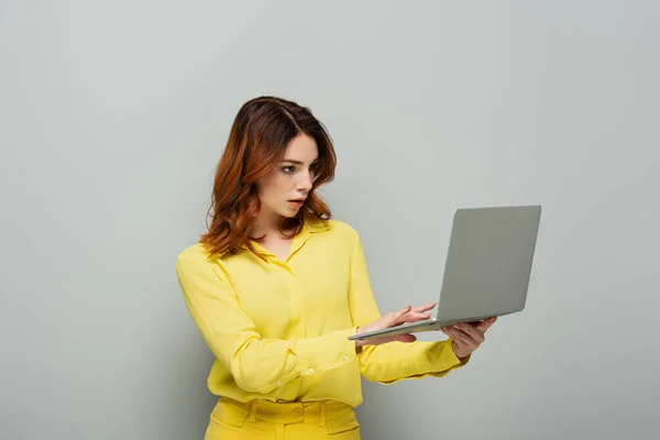 Wanita Terkonsentrasi Dalam Blus Kuning Mengetik Pada Laptop Pada Abu — Stok Foto