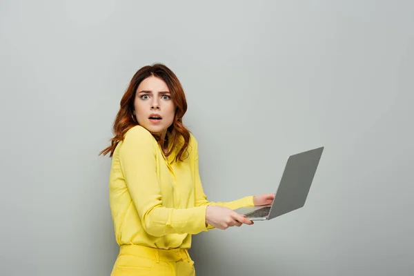 Shocked Woman Yellow Blouse Looking Camera While Holding Laptop Grey — Stock Photo, Image