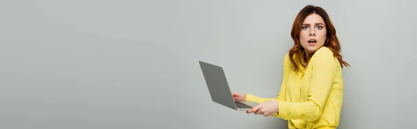 Erstaunte Frau Blickt Kamera Während Sie Laptop Auf Grauem Banner — Stockfoto