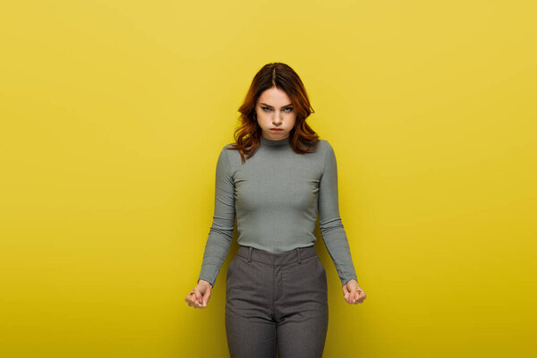 недовольная женщина, пыхтящая щеками, глядя в камеру на желтый цвет