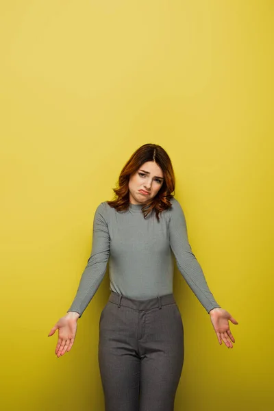 Verwirrte Frau Mit Welligem Haar Zeigt Achselzucken Geste Auf Gelb — Stockfoto