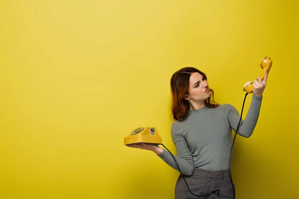 Desagradado Jovem Mulher Olhando Para Telefone Retro Amarelo — Fotografia de Stock