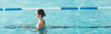 Spa merkezinde havuzda yüzen genç bir kadının yan görüntüsü, afiş 