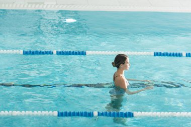 Spa merkezinde havuzda yüzen kadının yan görüntüsü 