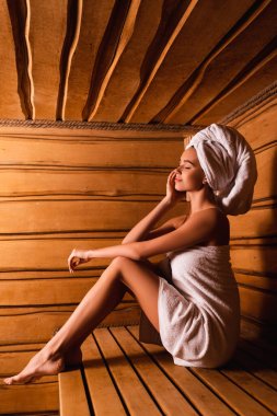 Side view of woman relaxing in sauna of spa center  clipart