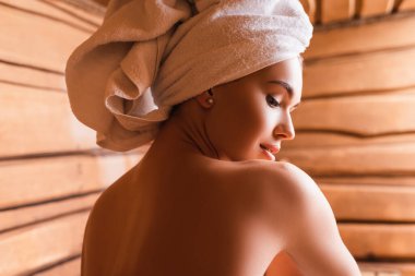 shirtless woman with towel on head relaxing in sauna  clipart
