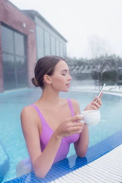 Mujer Joven Sosteniendo Teléfono Inteligente Taza Mientras Baña Piscina Aguas — Foto de Stock