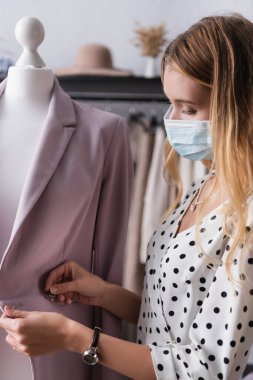 Tıbbi maskeli genç mal sahibi showroom 'daki spor ceketi ayarlıyor.