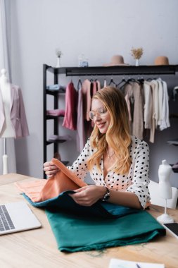 Şov salonunda kumaş örnekleri seçen neşeli iş kadını, bulanık önplan