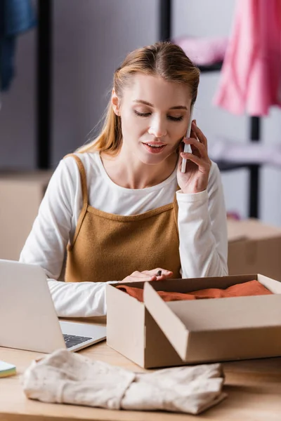 Young Businesswoman Talking Mobile Phone Carton Box Laptop Blurred Foreground — 스톡 사진