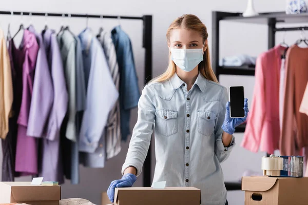 Young Showroom Proprietor Safety Mask Showing Smartphone Blank Screen Boxes — Stock Photo, Image