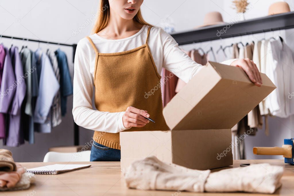 cropped view of seller collecting order in clothes showroom, blurred foreground