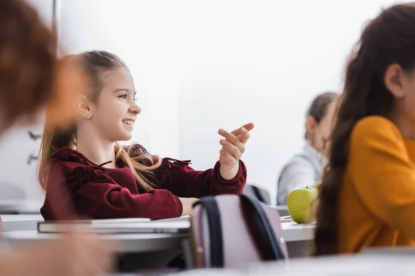 Positive Pupil Sitting Apple Book Laptop Blurred Foreground Classroom — Stock Photo, Image
