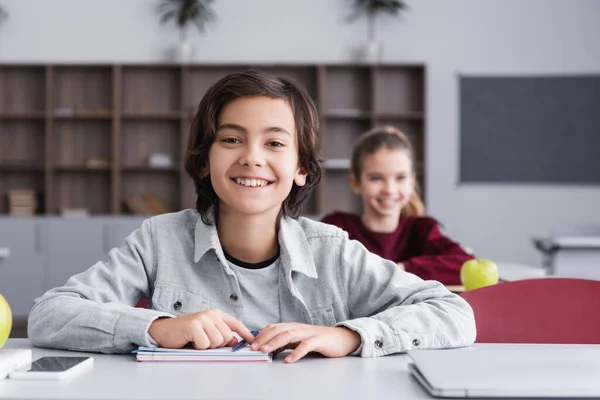 Smiling Child Looking Camera Devices Notebook Desk Classroom — Stock Photo, Image
