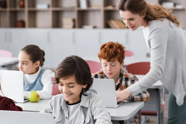 Nauczyciel Pomaga Uczniowi Pracować Laptopie Podczas Lekcji Niewyraźne Tło — Zdjęcie stockowe