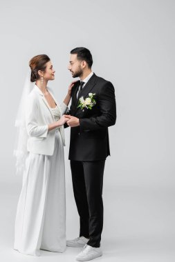 Gülümseyen gelin beyaz arka planda Arap damadı kucaklıyor. 