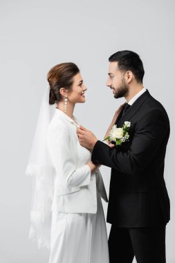 Neşeli gelinin yandan görünüşü Gri üzerine izole edilmiş Müslüman damada bakıyor 