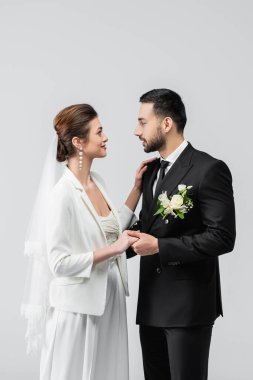 Gri renkte izole edilmiş gülümseyen gelinin elini tutan Arap damat. 