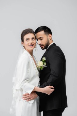 Düğün duvağı takmış, gri renkte, Müslüman damadın yanında duran pozitif gelin. 