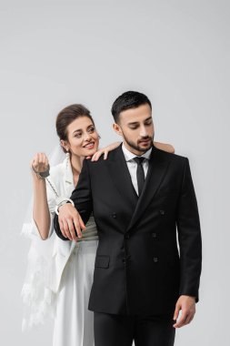 Gülümseyen gelin, gri renkte kelepçeli Arap damadın yanında duruyor. 