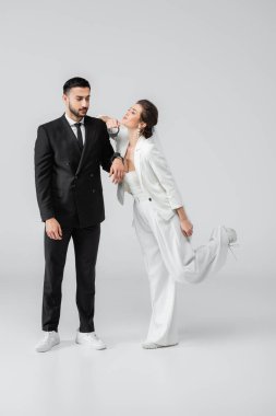 Beyaz arka planda kelepçeli Arap damadın yanında duran mutlu gelin.