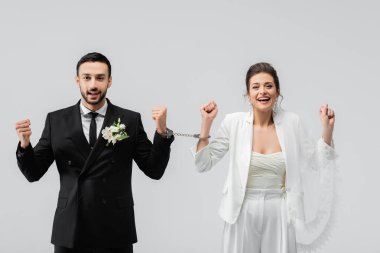 Mutlu ırklar arası kelepçeli bir çift yeni evli. Evet, gri renkte izole edilmiş bir jest. 