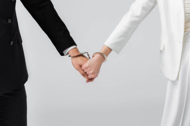 Gelin ve damadın kelepçeli görüntüsü gri renkte izole edilmiş. 