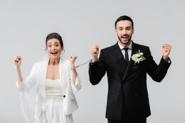 Elleri kelepçeli gelin ve damat heyecanlı. Evet, gri renkte izole edilmiş. 