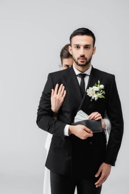 Müslüman damat kameraya bakarken gelin gri cüzdandan para alıyor. 