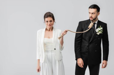 Boynunda düğümle kızgın bir Arap damat Gri üzerinde izole edilmiş gülen geline bakıyor. 