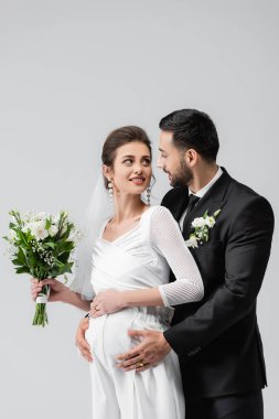 Hamile gelin takım elbiseli Müslüman damada bakıyor. 