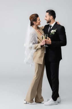 Mutlu, etnik çeşitliliğe sahip yeni evliler birbirlerine bakarken ellerinde şampanya bardaklarıyla griye bulanmışlar.