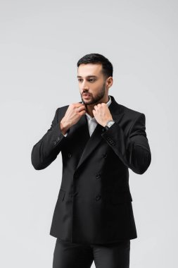 Zarif müslüman adam yakasını düzeltirken yüzünü gri renge çeviriyor.