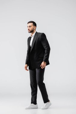Siyahlı, zarif takım elbiseli ve spor ayakkabılı genç bir Arap 'ın gri renkli bakışları.