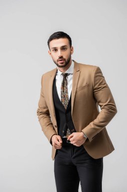 Gri renkli poz verirken kameraya bakan modaya uygun bir Arap.