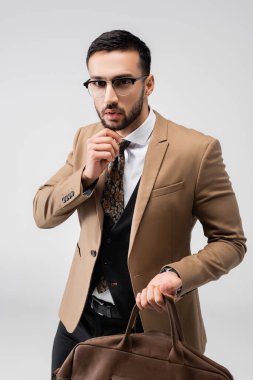 Gri renkli kameraya bakarken deri çanta tutan şık Müslüman adam.