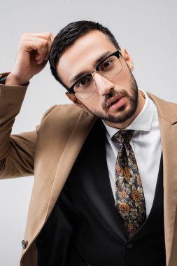 Gözlüklü modaya uyan Müslüman adam. Gri renkte yalnız başına, eli yakın poz veriyor.