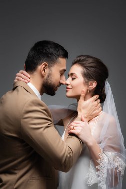 Neşe dolu ırklar arası yeni evliler. Gri yolda yüz yüze sarılıyorlar.