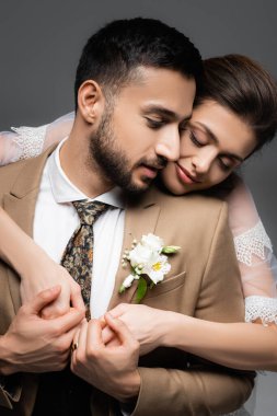 Mutlu gelin, gri renkte izole edilmiş Arap damadı kucaklıyor.