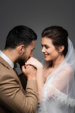 Gri yolda izole edilmiş neşeli gelinin elini öpen zarif Müslüman adam.